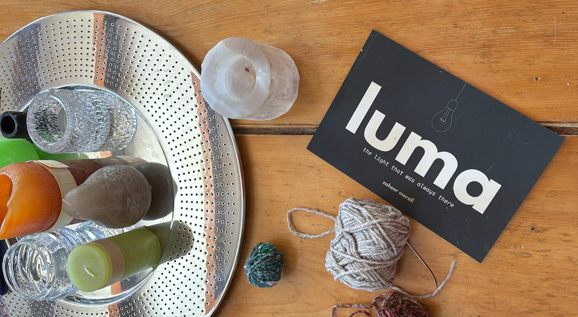 luma on a wooden table among candles, stones and yarn